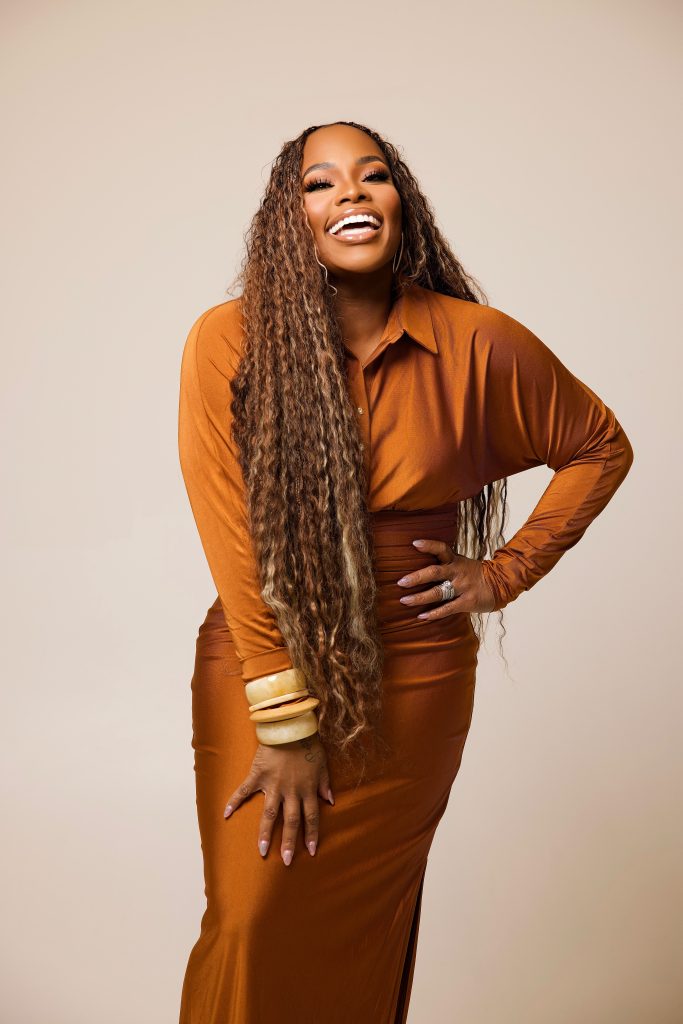 Tasha Cobbs Leonard posing in a brown outfit for a promotional portrait
