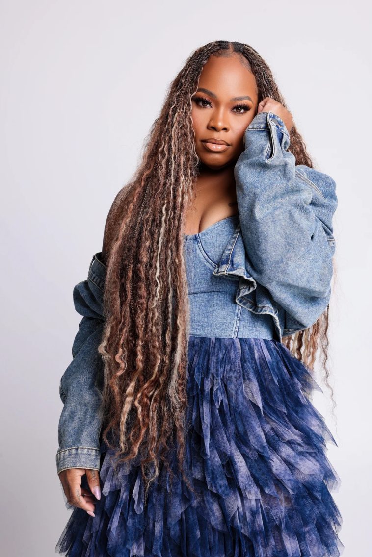 Tasha Cobbs Leonard posing in a blue denim outfit ahead of her TASHA Unscripted live album